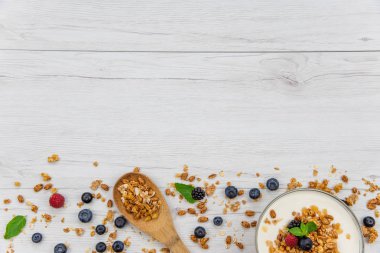 Kase Yoğurt granola ve taze meyveler ve tahta kaşık tam whit granola Beyaz ahşap masa, arka plan, üstten görünüm, kopya alanı ile