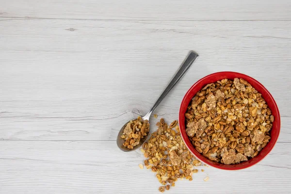 Tam bir kaşık Beyaz ahşap masa, üstten görünüm üzerinde kırmızı bir kase, granola