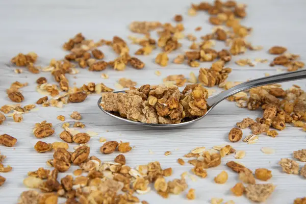 Beyaz ahşap masa üzerinde granola dolu kaşık