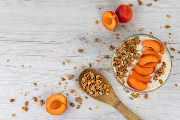 Kayısı yoğurt ve bir tahta kaşık granola bir beyaz ahşap masa, üstten görünüm, kopya alanı dolu dolu bir kase