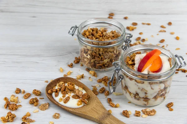 Granola ve yoğurt, tahta kaşık whit granola ve kayısı Beyaz ahşap masa üzerinde dolu bir kavanoz