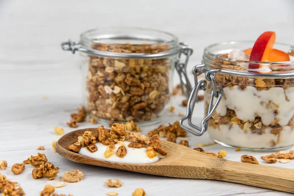 Granola ve yoğurt, tahta kaşık whit granola ve kayısı Beyaz ahşap masa üzerinde dolu bir kavanoz
