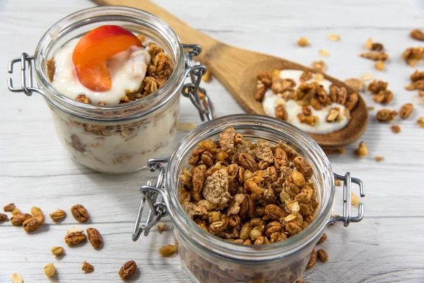 Granola, ahşap ile bir kavanoz dolu kaşık Beyaz ahşap masa, yakın-up, seçici odak whit granola