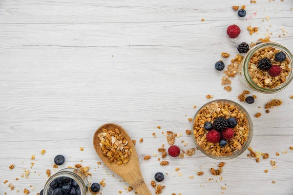 Kavanoz granola ve taze meyveleri ve tahta kaşık tam whit granola üzerinde beyaz ahşap masa, arka plan, üstten görünüm, tam alanı Kopyala