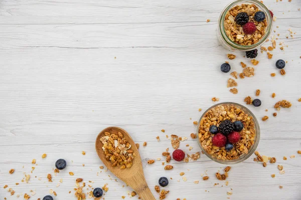 Kavanoz granola ve taze meyveleri ve tahta kaşık tam whit granola üzerinde beyaz ahşap masa, arka plan, üstten görünüm, tam alanı Kopyala