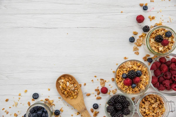 Kavanoz granola ve taze meyveleri ve tahta kaşık tam whit granola üzerinde beyaz ahşap masa, arka plan, üstten görünüm, tam alanı Kopyala