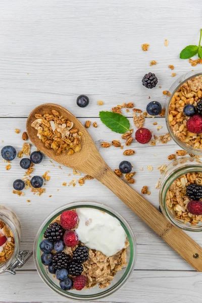 Granola, yoğurt ve taze meyveleri ve tahta kaşık tam whit granola, üstten görünüm seçici odak ile dolu kavanoz