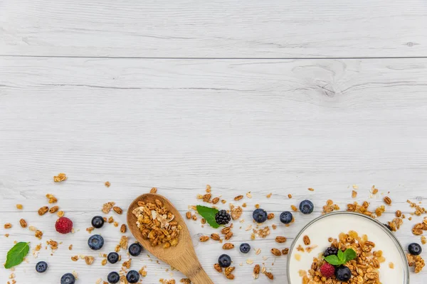 Kase Yoğurt granola ve taze meyveler ve tahta kaşık tam whit granola Beyaz ahşap masa, arka plan, üstten görünüm, kopya alanı ile