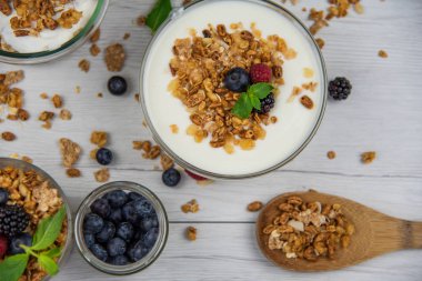 Kavanoz granola, yoğurt ve taze meyveleri ve tahta kaşık tam whit granola Beyaz ahşap masa, üstten görünüm, seçici odak ile tam