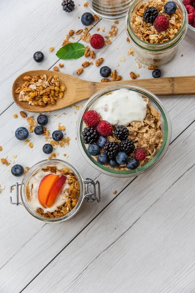 Granola, yoğurt ve taze meyveleri ve tahta kaşık tam whit granola, üstten görünüm seçici odak ile dolu kavanoz