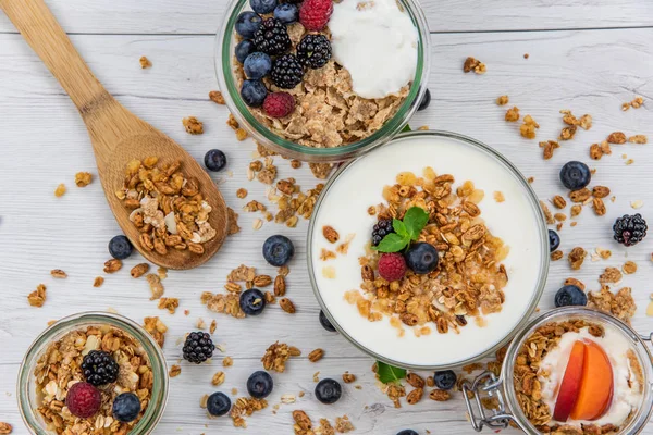 Kavanoz granola, yoğurt ve taze meyveleri ve tahta kaşık tam whit granola Beyaz ahşap masa, üstten görünüm, seçici odak ile tam