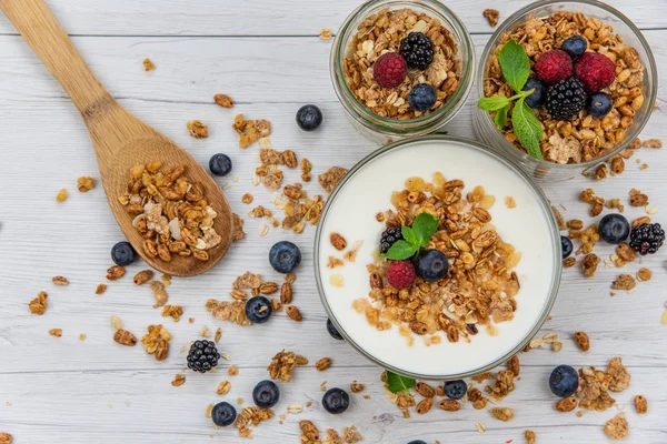 Kavanoz granola, yoğurt ve taze meyveleri ve tahta kaşık tam whit granola Beyaz ahşap masa, üstten görünüm, seçici odak ile tam