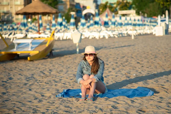 Hayran ve deniz esinti zevk kumsalda güneş doğarken oturan bir kız