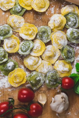 Ev yapımı taze İtalya Mantı makarna un, fesleğen, domates, arka plan, üstten görünüm ile ahşap masa üzerine.