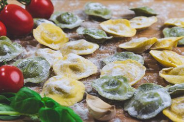 Ev yapımı taze İtalya Mantı makarna un, fesleğen, domates, arka plan, ahşap masa üzerine yakın-up.