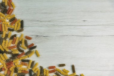 Çiğ çiğ üç renkli düdük durum buğday makarna ıspanak ve beyaz ahşap masa, kopya alanı üzerinde domates ile.