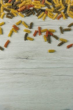 Çiğ çiğ üç renkli düdük durum buğday makarna ıspanak ve beyaz ahşap masa, kopya alanı üzerinde domates ile.