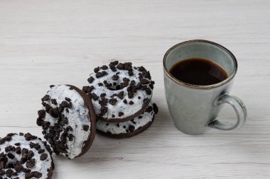 Beyaz ahşap arka planda çörek ve kahve fincanı, yakın plan.