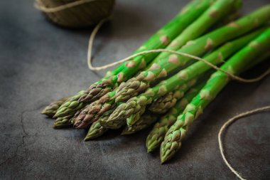Siyah taş zemin üzerinde yeşil taze kuşkonmaz.