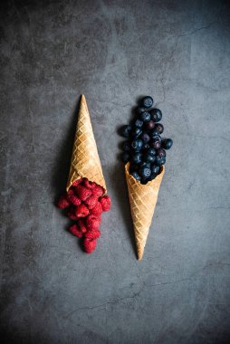 Koyu taştan arka planda waffle külahında taze böğürtlen, üst manzara. Sağlıklı yiyecekler ve çöl kavramı.