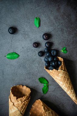 Koyu taştan arka planda böğürtlen ve krep külahları, üst manzara. Sağlıklı yiyecekler ve çöl kavramı.