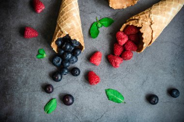 Koyu taştan arka planda waffle külahında taze böğürtlen, üst manzara. Sağlıklı yiyecekler ve çöl kavramı.