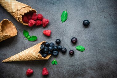 Koyu taştan arka planda waffle külahında taze böğürtlen, üst manzara. Sağlıklı yiyecekler ve çöl kavramı.