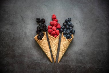 Koyu taştan arka planda waffle külahında taze böğürtlen, üst manzara. Sağlıklı yiyecekler ve çöl kavramı.