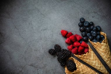 Koyu taştan arka planda waffle külahında taze böğürtlen, üst manzara. Sağlıklı yiyecekler ve çöl kavramı. Boşluğu kopyala.