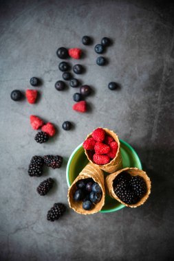 Koyu taştan arka planda waffle külahında taze meyveler. Üst Manzara. Sağlıklı yiyecekler ve çöl kavramı.