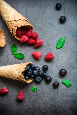 Koyu taştan arka planda waffle külahında taze böğürtlen, üst manzara. Sağlıklı yiyecekler ve çöl kavramı.