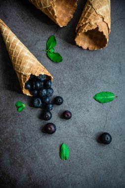 Koyu taştan arka planda böğürtlen ve krep külahları, üst manzara. Sağlıklı yiyecekler ve çöl kavramı.