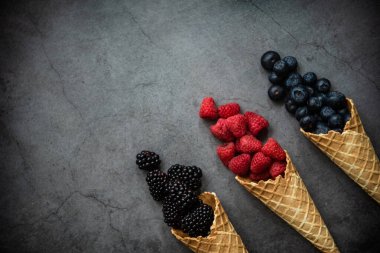 Koyu taştan arka planda waffle külahında taze böğürtlen, üst manzara. Sağlıklı yiyecekler ve çöl kavramı. Boşluğu kopyala.