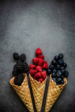 Koyu taştan arka planda waffle külahında taze böğürtlen, üst manzara. Sağlıklı yiyecekler ve çöl kavramı. Boşluğu kopyala.