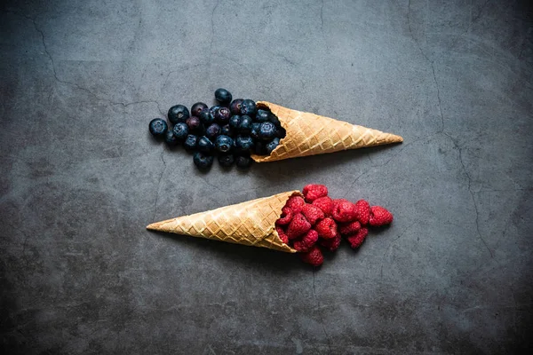 Koyu taştan arka planda waffle külahında taze böğürtlen, üst manzara. Sağlıklı yiyecekler ve çöl kavramı.
