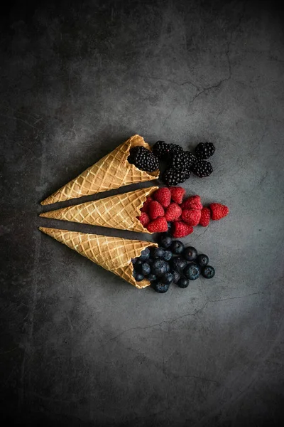 Koyu taştan arka planda waffle külahında taze böğürtlen, üst manzara. Sağlıklı yiyecekler ve çöl kavramı.