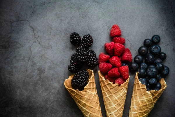 Koyu taştan arka planda waffle külahında taze böğürtlen, üst manzara. Sağlıklı yiyecekler ve çöl kavramı.