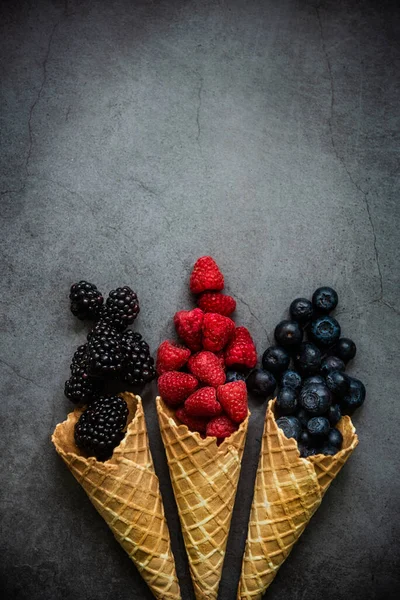 Koyu taştan arka planda waffle külahında taze böğürtlen, üst manzara. Sağlıklı yiyecekler ve çöl kavramı. Boşluğu kopyala.