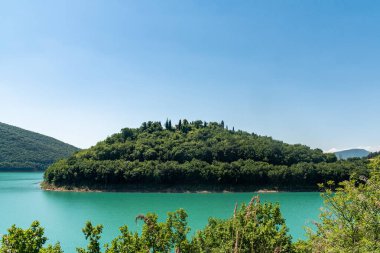 Yazın mavi gökyüzü, yeşil ve renkli dağlarla Cingoli Gölü manzarası, İtalya.