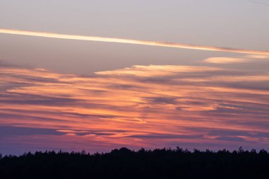  Dramatik bir günbatımı gökyüzünü turuncu, pembe ve mor çizgilerle resmediyor..