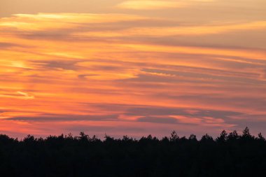  Dramatik bir günbatımı gökyüzünü turuncu, pembe ve mor çizgilerle resmediyor..