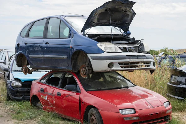 Dikey olarak hurdalığa yığılmış arabalar çarpıcı otomotiv hasarı ve endüstriyel geri dönüşüm gösteriyor..
