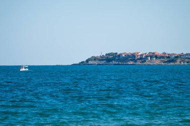 Küçük bir tekne sakin kıyı sularında eski Nesebar 'ın büyüleyici bir yamaç kasabasına doğru süzülüyor.