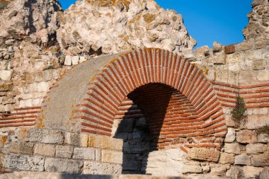  Ancient stone wall with a red brick arch under a clear blue sky in Nesebar, Bulgaria
