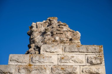Weathered stone wall with rectangular blocks and crumbled upper layers stands beneath a clear blue sky in Nesebar, Bulgaria