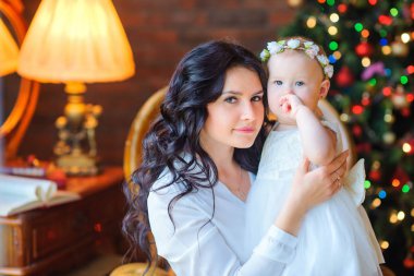 güzel anne küçük kızı şenlikli Noel ağacı yakın bir sandalyede oturuyor ve hugs