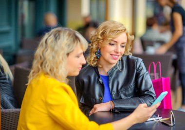 iki güzel kız bir kafede otururken internet üzerinden alışveriş gülüyorsun