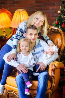 mutlu aile sit birlikte oturup bir sandalye ve sarılmak, Noel ağacının yanındaki