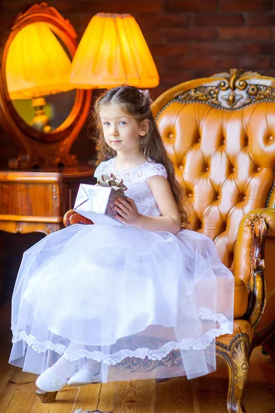 Όμορφο Κοριτσάκι Ένα Λευκό Φόρεμα Κατέχει Ένα Δώρο Ενώ Κάθεται — Φωτογραφία Αρχείου