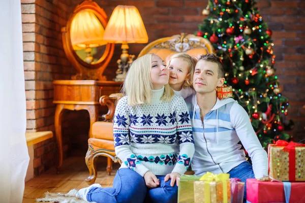 幸せなご家族のお祝いクリスマス ツリー 娘の両親は 肯定的な感情を抱いてのささやかな贈り物を持って近くの床の上に座って — ストック写真